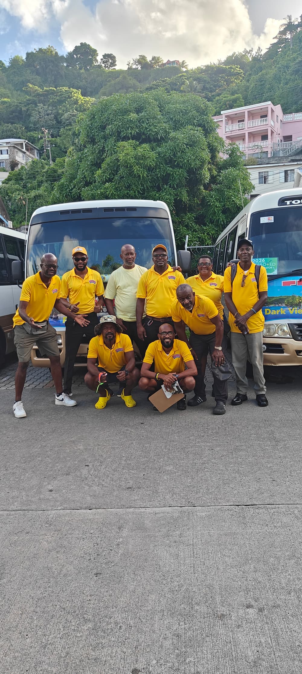 The Fraser Taxi & Tours team in their branded yellow shirts, in front of the fleet